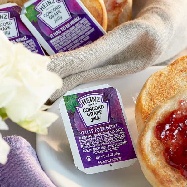 A bagel with Heinz Concord grape jelly on a plate.