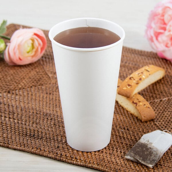 A white Dart ThermoGuard paper hot cup filled with tea sits on a table with cookies.