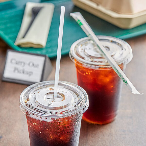 Two plastic cups with EcoChoice PLA straws and brown liquid on a table.