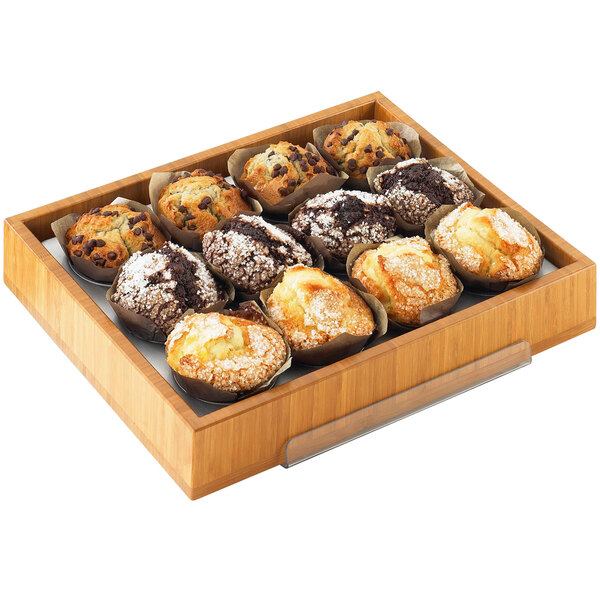 A Cal-Mil bamboo display tray filled with assorted pastries on a table in a bakery.