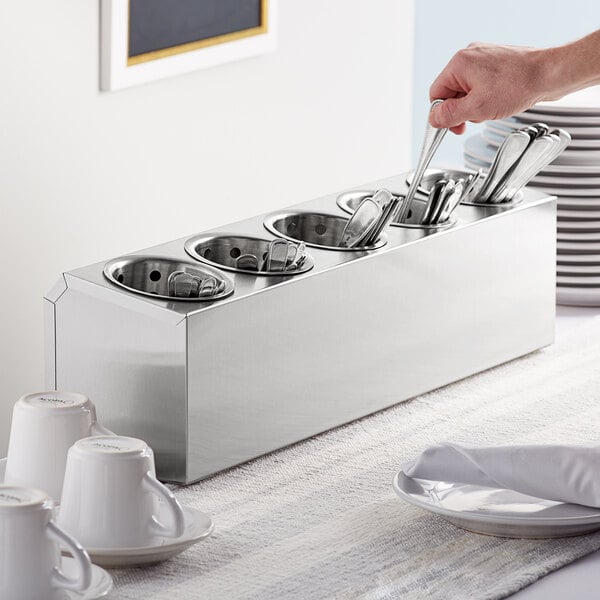 A person holding a Choice stainless steel flatware organizer with utensils inside.