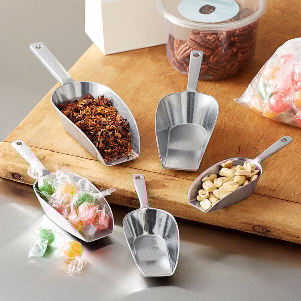 A Choice aluminum flat bottom scoop on a table with a scoop of peanuts.