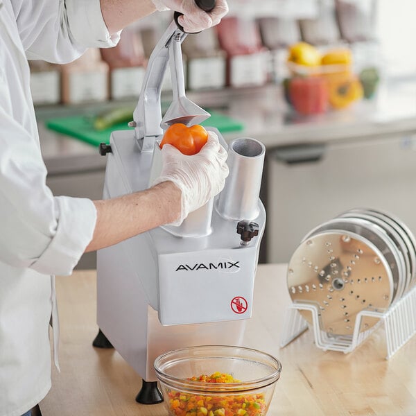 A person using an AvaMix commercial food processor to dice bell peppers.