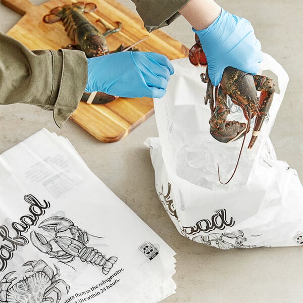 A person wearing blue gloves holding a Handled Seafood Bag with a lobster inside.