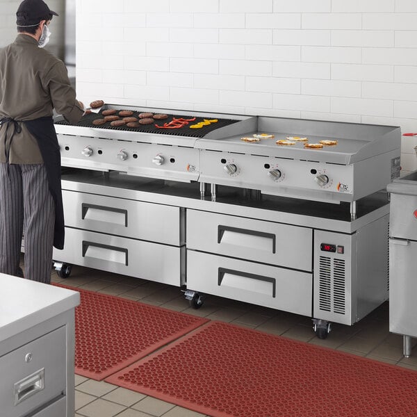 A man wearing a black apron cooking on a Cooking Performance Group chef base with a gas griddle.