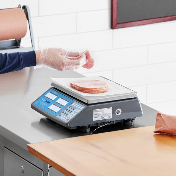 A digital price computing scale with a stack of sliced deli meat being weighed on it.