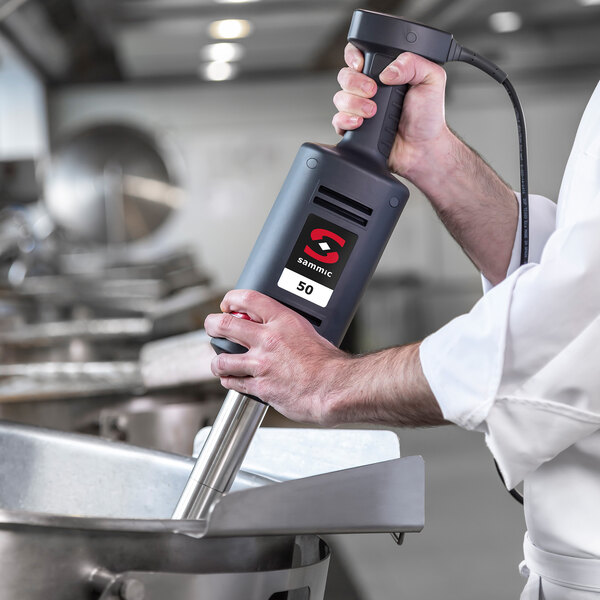 A person using a Sammic XM-52 heavy-duty commercial immersion blender in a professional kitchen.