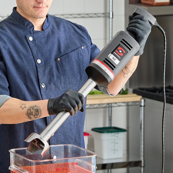 A Sammic XM-51 heavy-duty 16-inch variable speed immersion blender being used in a commercial kitchen.