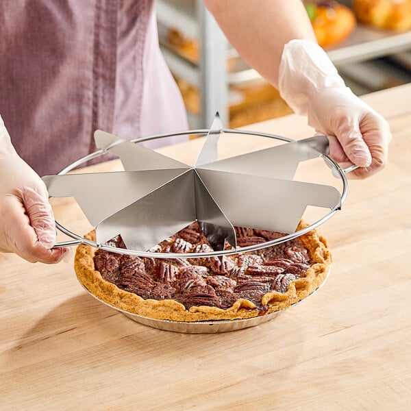 A person using a Choice stainless steel pie cutter to cut a pie.