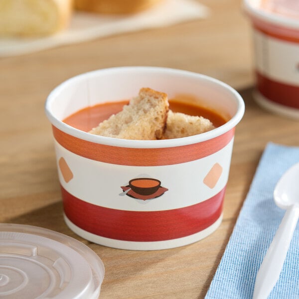 An 8 oz. double poly-coated paper soup cup with a vented plastic lid, filled with soup and bread pieces.