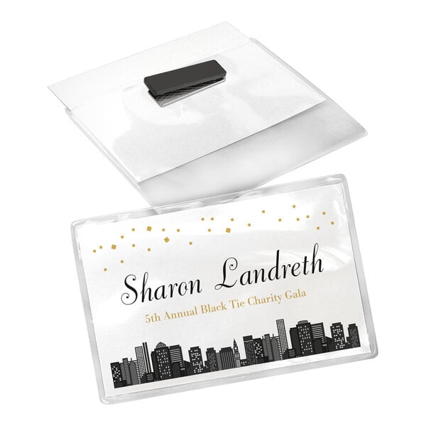 A clear plastic name badge with a magnetic backing, displaying a card with a city skyline design and event details.