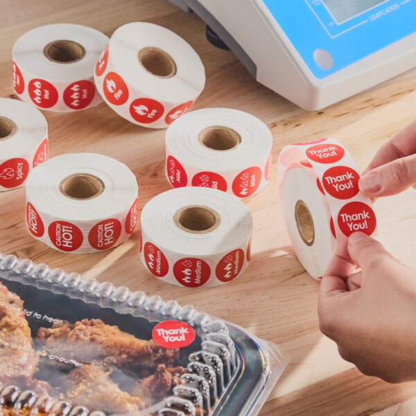 A set of rolls of red adhesive labels with various messages such as 'Thank You!' and 'Caution Hot!' used for packaging.