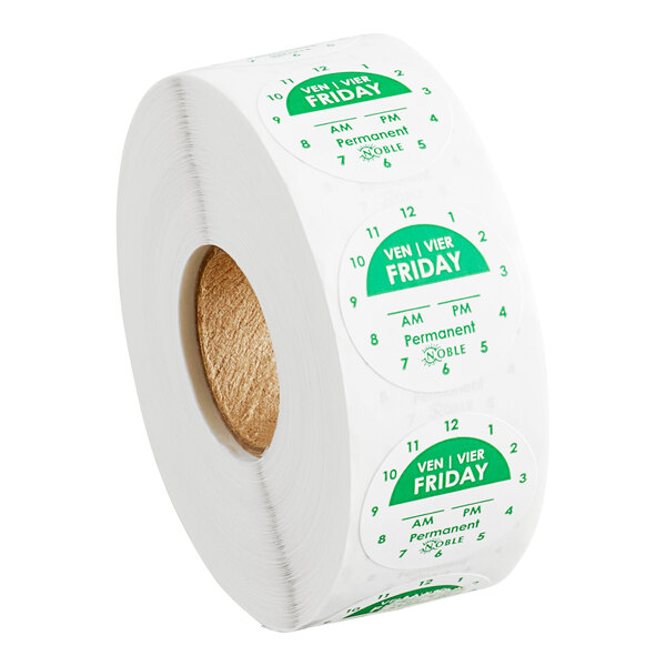 A roll of round green and white labels marked for Friday with clock times and permanent adhesive, used for day-of-the-week food labeling.