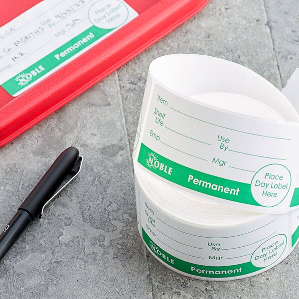 A roll of Noble Products Universal Day of the Week labels next to a pen.
