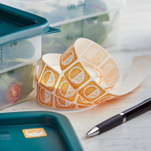 A roll of Noble Products Tuesday Dissolvable Day of the Week labels on a tray next to a black and silver pen.