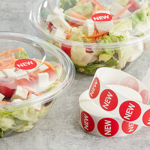 A plastic container of salad with a Point Plus New Red label next to a roll of Point Plus New Red labels.