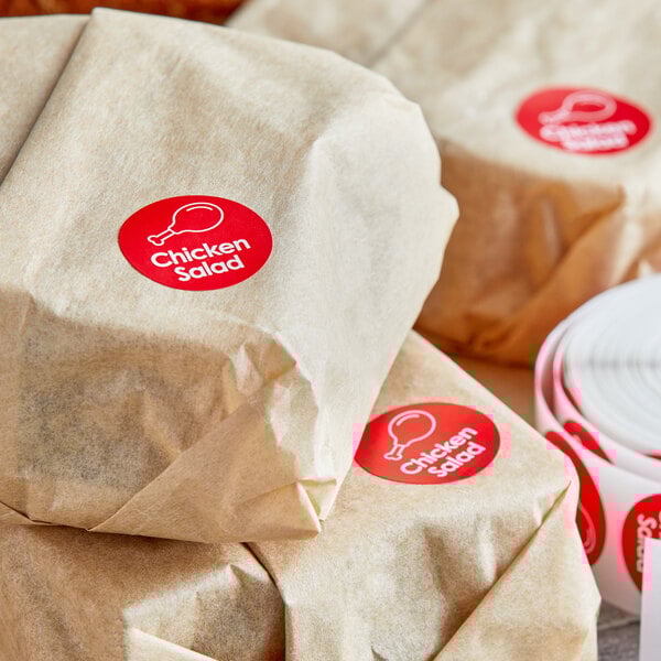 A roll of Point Plus Chicken Salad red labels on brown packages of food.