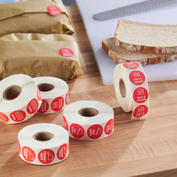 A roll of red permanent labels for chicken salad sandwiches, each label featuring text and a sandwich graphic.