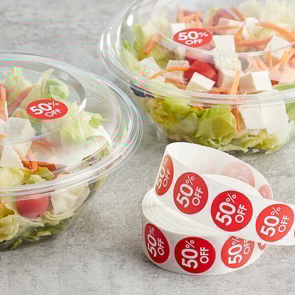 A salad in a plastic container with a red Point Plus label next to a roll of Point Plus red labels.