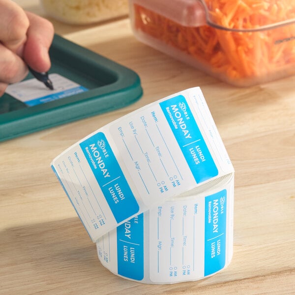 A roll of Noble brand removable Monday day of the week labels, each measuring 2 inches by 2 inches.