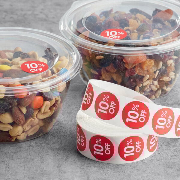 A roll of Point Plus red labels with food labels on plastic containers filled with nuts and dried fruit.