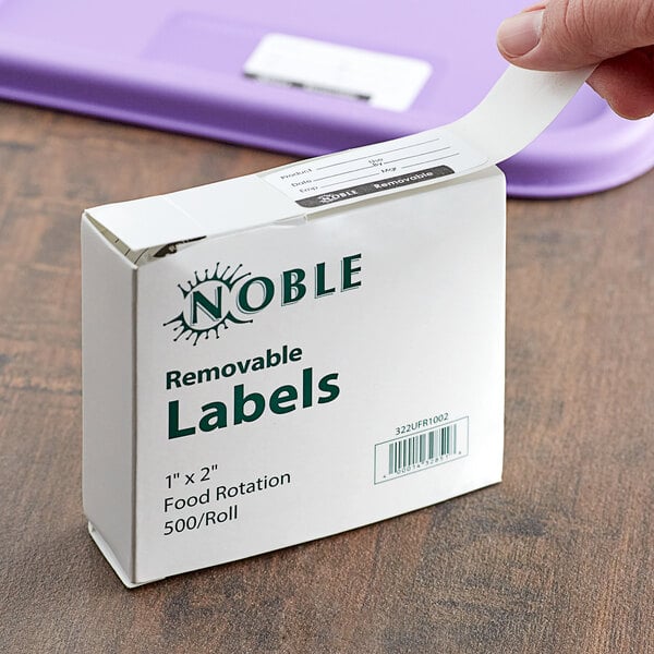 A hand holding a white box of Noble Products removable food rotation labels.