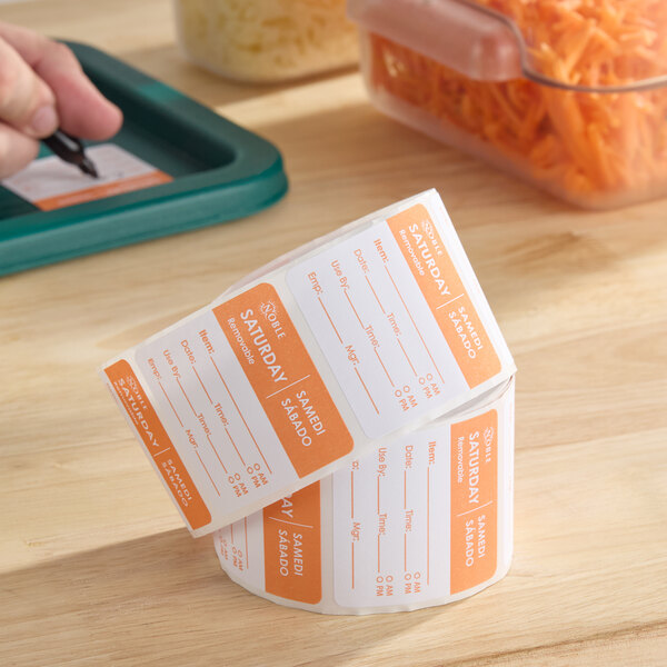 A roll of removable orange and white Saturday day of the week labels for food storage and organization.