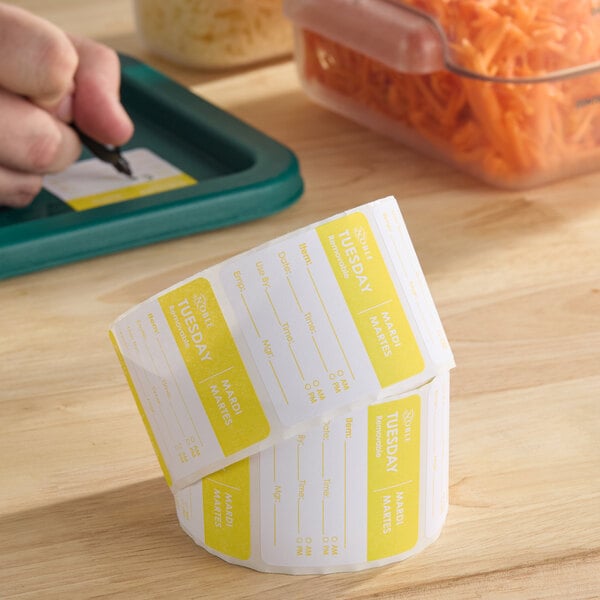 A roll of yellow and white removable day of the week labels marked for Tuesday.
