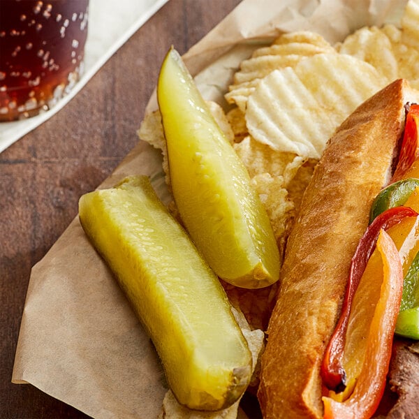 A sandwich with Heinz quarter cut pickle spears and chips on a paper plate.