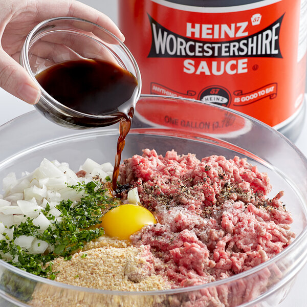 A hand pouring Heinz Worcestershire Sauce into a bowl of ground meat.