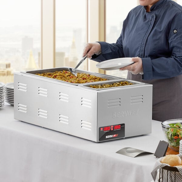 A woman serving food from a ServIt countertop food warmer at a hotel buffet.