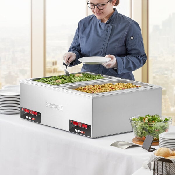 A woman serving food from a ServIt countertop food warmer at a buffet.