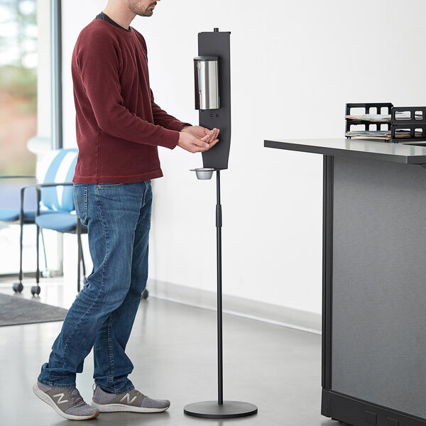 A man using a Lavex stainless steel foaming soap and sanitizer station.