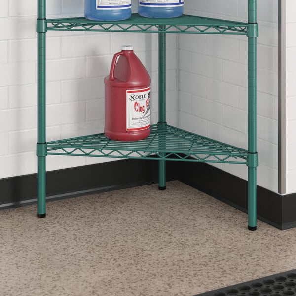 A green metal Regency triangle shelf holding jugs of chemicals and cleaning supplies.