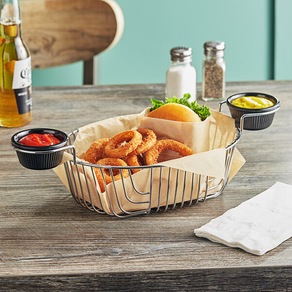 An Acopa chrome wire basket with ramekin holders filled with onion rings on a table.