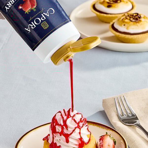 A cupcake with Capora strawberry flavoring sauce being poured onto it.