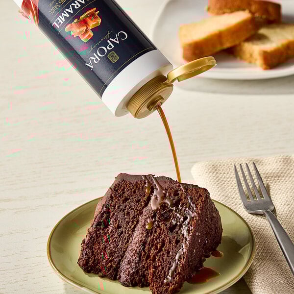 A piece of chocolate cake with Capora caramel syrup on a green plate with a fork.