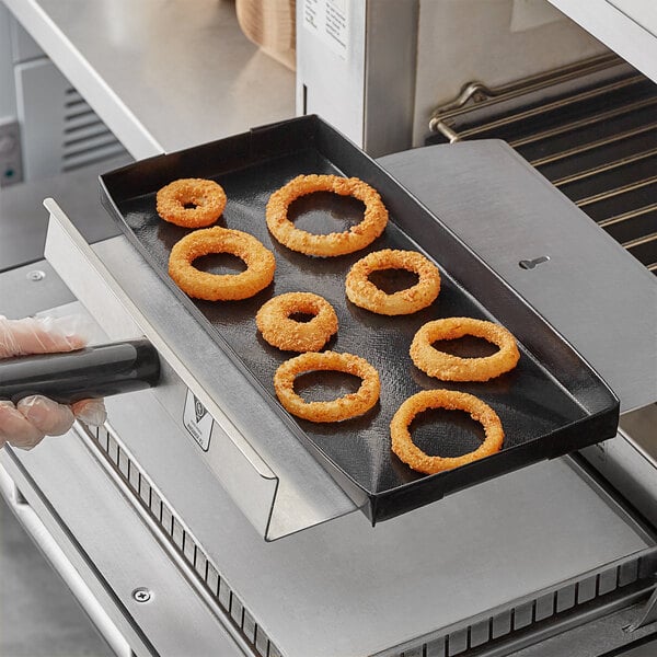 A hand holding a Baker's Mark solid non-stick pan of fried onion rings.