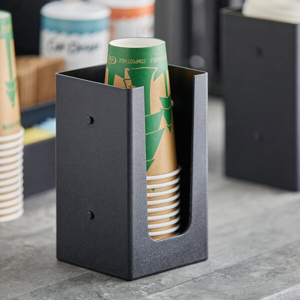 A black holder with a green cup in it.