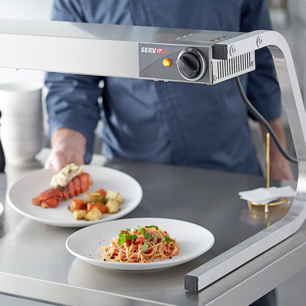 A chef using a ServIt strip warmer to keep food warm on a table.