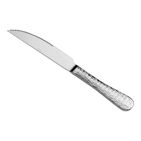 A stainless steel steak knife with a serrated blade and a textured handle is shown against a white background.