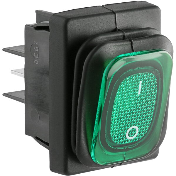 A green push button switch with a white text on a black square.