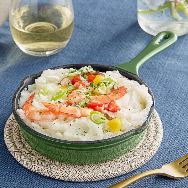 A Valor fern green enameled cast iron skillet with shrimp and vegetables on a table.