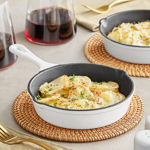 A Valor 6" Arctic White Enameled Mini Cast Iron Skillet filled with food on a table.