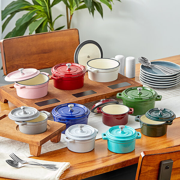 A table with a stack of Valor cranberry apple enameled mini cast iron pots with covers.