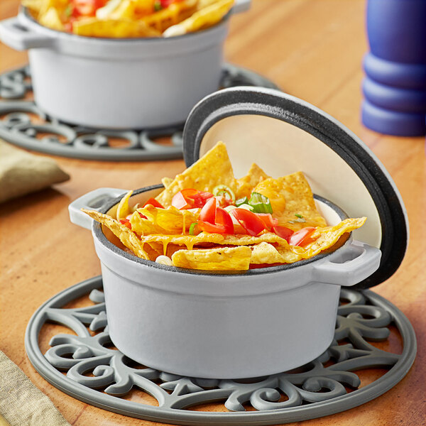 A Valor enameled cast iron pot filled with nachos, cheese, tomatoes, and jalapenos.