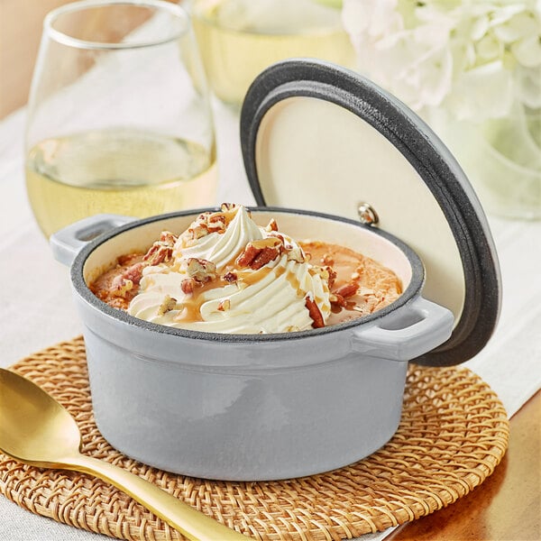 A Valor mini enameled cast iron pot with a cover on a table with a bowl of food and a spoon.