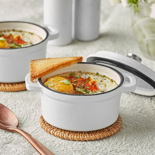 Two white Valor enameled cast iron pots with food inside.