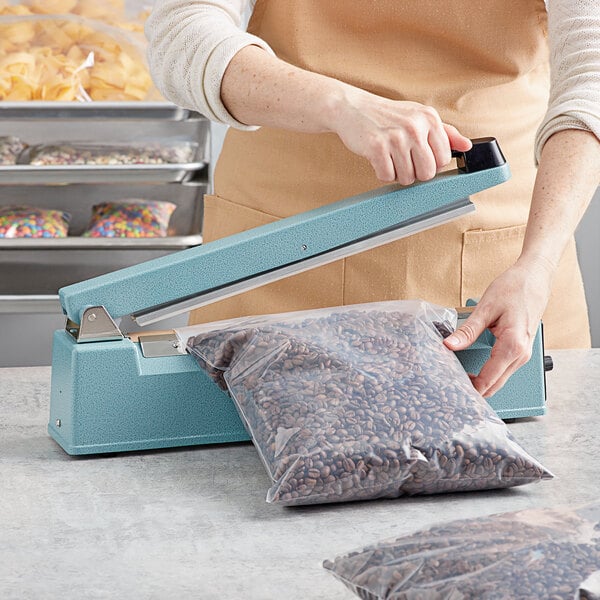 A person using a Thunder Group manual impulse bag sealer to seal a bag of beans.