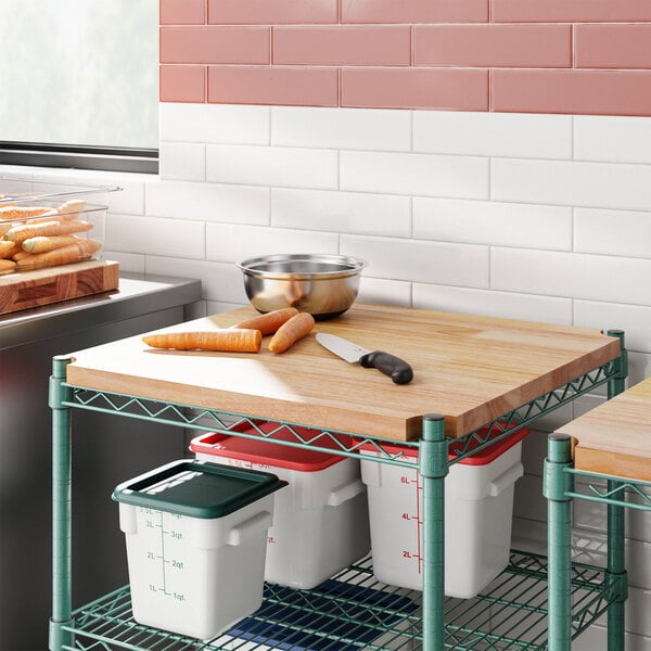 A Regency hardwood cutting board insert on a green metal shelf with food on it.